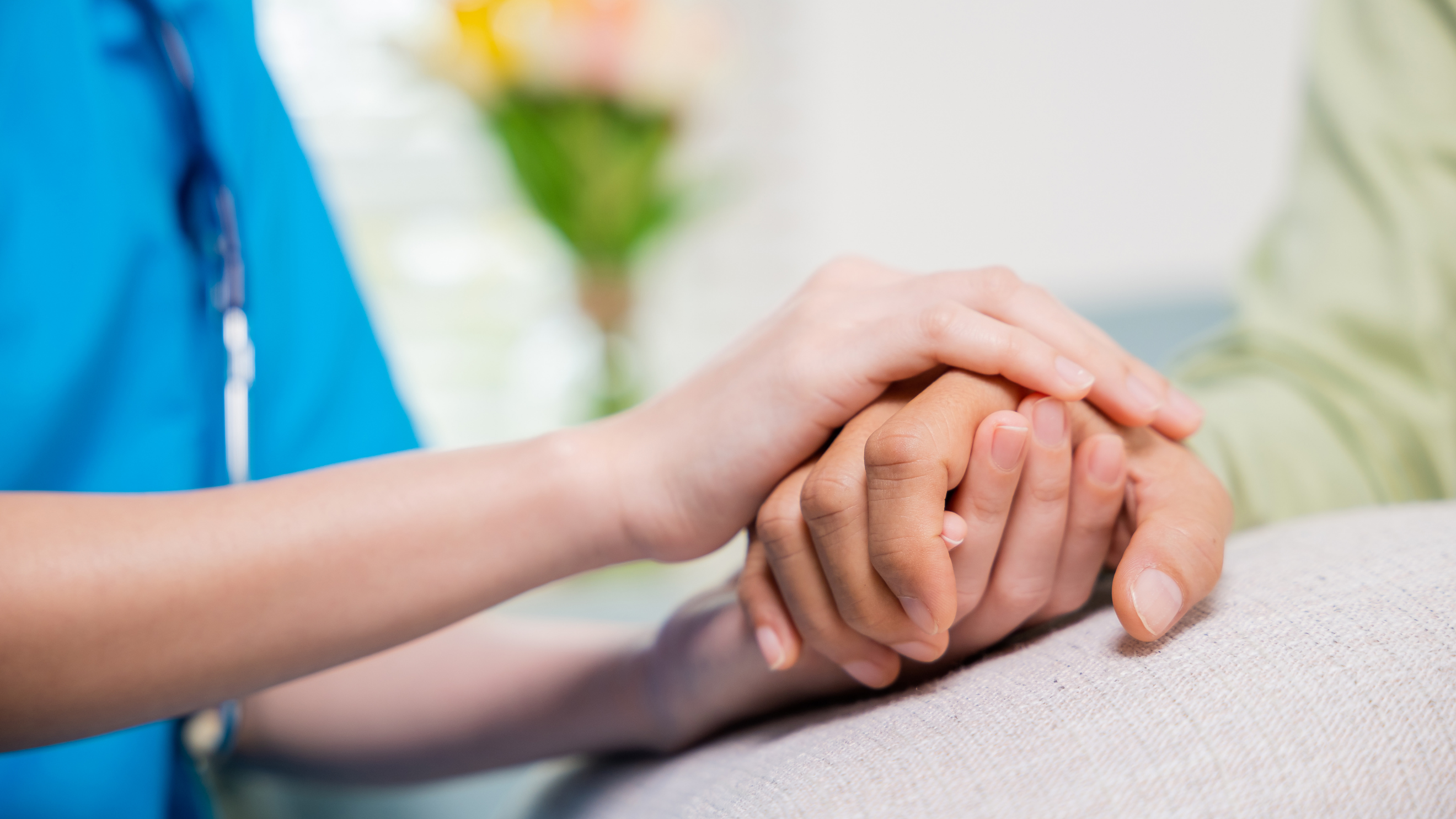 A Zoe's Healthcare Services caregiver holding the hand of an elderly woman receiving in-home care in Baltimore County, Maryland