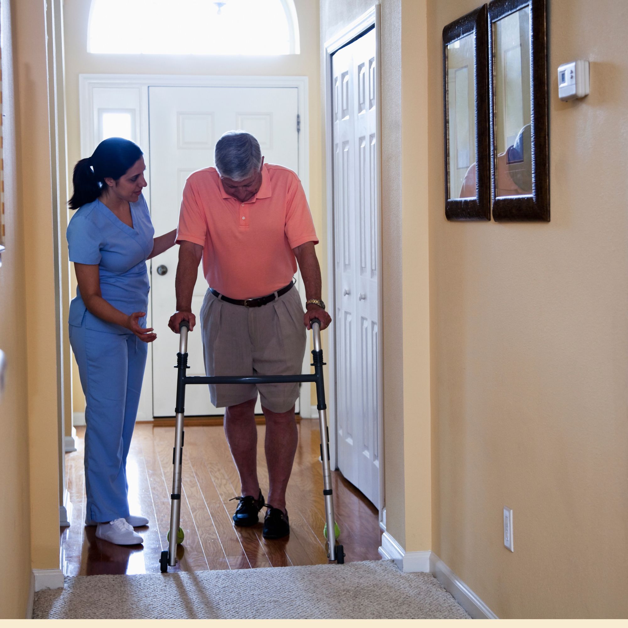 A Zoe's Healthcare Services caregiver supporting an elderly man using a walker in his home